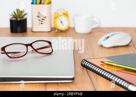 the closed notebook computer was placed on the desk in the room, women's glasses put away Stock Photo