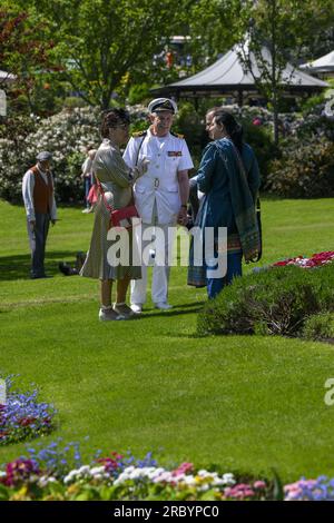 Person in 1940's fashion (officer's outfit) at nostalgic re-enactment weekend, standing having a chat - sunny Haworth Park, West Yorkshire England UK. Stock Photo