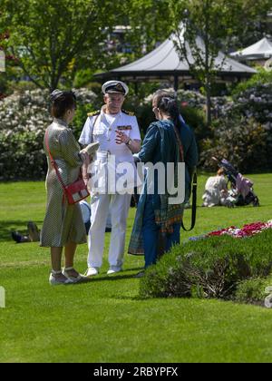 Person in 1940's fashion (officer's outfit) at nostalgic re-enactment weekend, standing having a chat - sunny Haworth Park, West Yorkshire England UK. Stock Photo