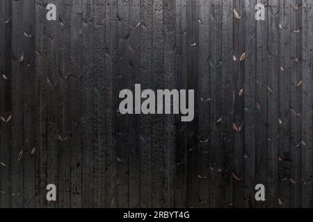 Vertical black dark burned wood vertical linear pattern facade. Stock Photo