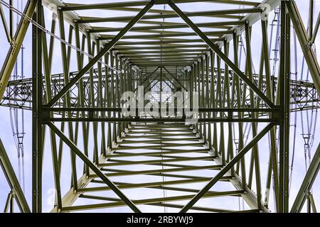 Steel beams, wires and a bird's nest in a huge power pole photographed directly from below against the sky Stock Photo