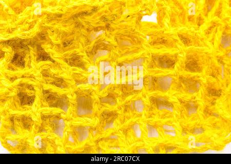 Knitted fabric made of yellow jute, mesh. Close-up. Background. Stock Photo