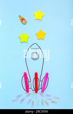 Creative composition with drawn rocket and different stationery on blue background Stock Photo