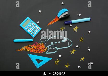 Creative composition with drawn rocket and different stationery on black chalkboard Stock Photo
