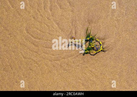 Small piece of plastic fishing net on a sandy beach in Wales Stock Photo
