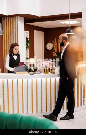 Businessman with passport id papers preparing to do check in for room reservation, reviewing documents at front desk reception. Client travelling for work to attend official meetings. Stock Photo