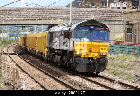 Direct Rail Services class 66 loco on West Coast Main Line passing through Carnforth on 5th July 2023 with yellow wagons on civil engineer train. Stock Photo