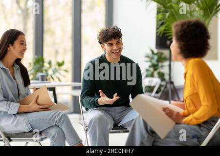 Teamwork concept. International students talking and discussing their educational project together in coworking space Stock Photo
