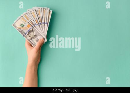 A lot of bills of 100 dollars in hands are folded in a fan on a green background top view with space for text. Currency, banknotes in female hands Stock Photo