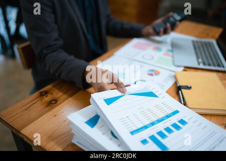 businessman or accountant working on calculator and laptop computer to calculate business data during using accountancy document at office. Stock Photo