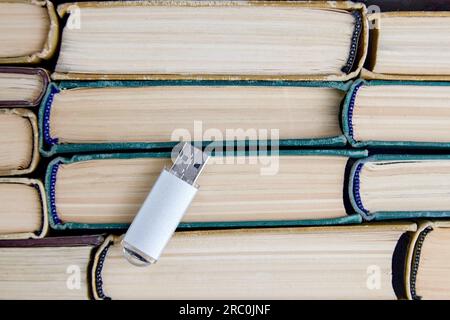 usb flash drive on background of stack of paper books. keepers of information and knowledge from different eras Stock Photo