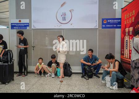 People seen waiting at Shenzhen North Railway station. High speed railway is a popular and affordable public transition for traveling between the cities and provinces in mainland China. As summer holiday starts, a lot of people take the high speed railway to travel within China, many of them bring their families and children as well. Stock Photo