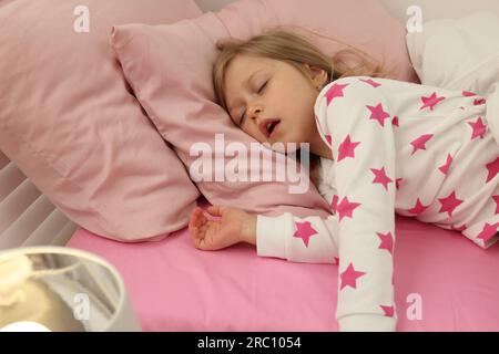 Little girl snoring while sleeping in bed Stock Photo