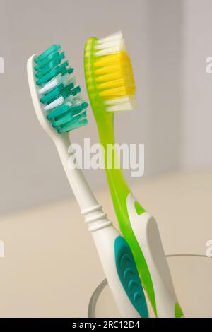New toothbrushes in glass holder on blurred background, closeup Stock Photo