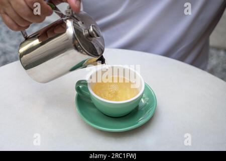 Pouring hot tea from pot to cup. Time for tea break. Stock Photo
