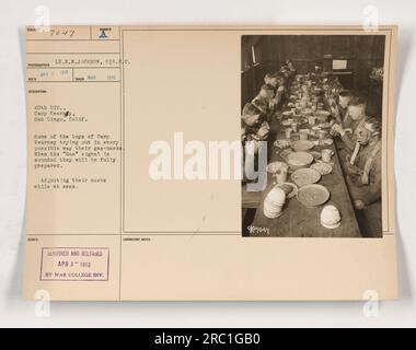 Members of the 40th Division at Camp Kearny in San Diego, California, are seen in this photograph from 1918. They are practising with their gas masks to ensure they are ready for any potential gas attacks. The soldiers are adjusting their masks while at mess, preparing themselves for the 'Gas' signal. Stock Photo