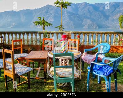 A charming rustic setting, with mismatched tables and chairs set for a morning tea break, overlooking Lake Phewa in Pokhara, Nepal. Stock Photo