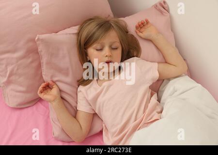 Little girl snoring while sleeping in bed Stock Photo