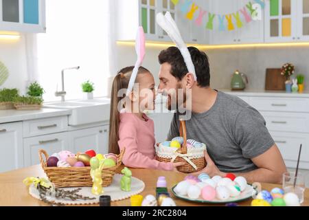 Father and his cute daughter with wicker basket full of Easter eggs in kitchen Stock Photo