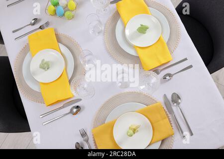 Festive table setting with glasses, painted eggs and plates, view from above. Easter celebration Stock Photo