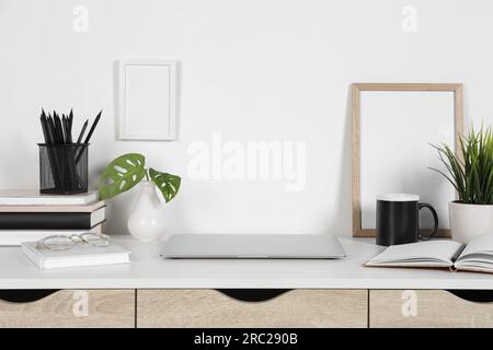 Cozy workspace with laptop, houseplants and stationery on wooden desk at home Stock Photo