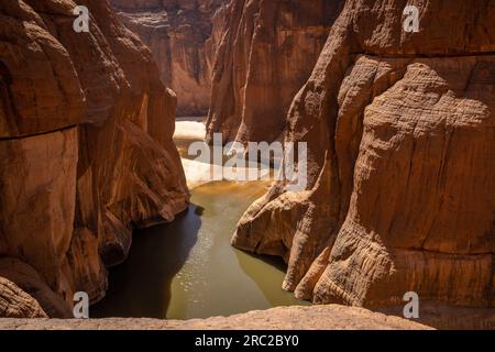 Overlooking the Guelta d'Archei, the undulating terrain echoes tales of ancient geological evolution. Elevated view. Stock Photo