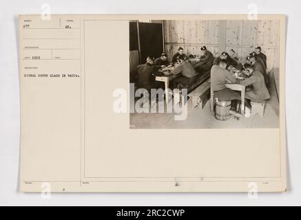 Members of the Signal Corps participating in a radio class during World War I. This photograph, taken in 1919, shows soldiers engaged in training exercises. The image is labeled as WIMBER 455 and was issued by the Signal Corps. The individuals in the photo can be seen taking notes and learning about radio technology. Stock Photo