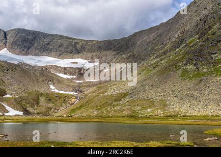 Glacier lake in a mountain valley with a small glacier Stock Photo