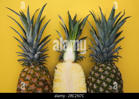 Whole and cut ripe pineapples on yellow background, flat lay Stock Photo