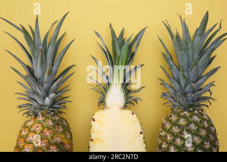 Whole and cut ripe pineapples on yellow background, flat lay Stock Photo