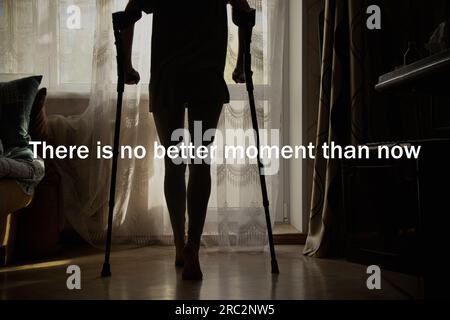 A young girl on crutches is trying to walk around the room and the text there is no better moment than now, motivation to train and move towards succe Stock Photo