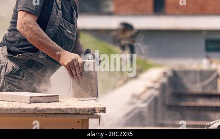 Close up of worker hand using circular saw in the process of cutting stone for paving pavement Stock Photo