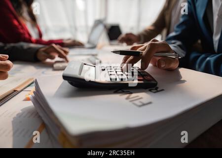 Business team meeting using calculator Work with charts and analyze business strategies. financial statistics sitting at the desk Stock Photo