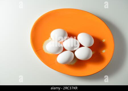 Fresh white eggs on an orage plate. White background. Stock Photo