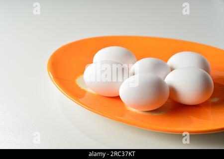 Fresh white eggs on an orage plate. White background. Stock Photo