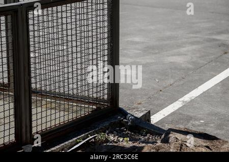 Detail of the exterior metal fence in broad daylight. Cement exterior with painted lines on the floor. Copy space Stock Photo