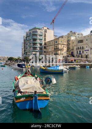 San Giljan (Saint Julian's), Malta - September 26th 2022: Traditional Maltese fishing boats called Luzzu moored in Spinola Bay. Stock Photo