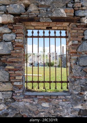 Elefsina, Attica Greece. 2023 European Capital of Culture. View through rusty window grid of old Olive Mill Factory and Open Air Theater. Vertical Stock Photo
