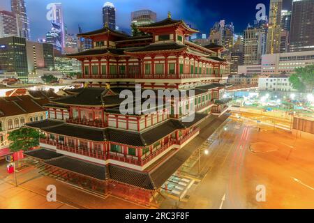 Buddha Tooth Relic Temple in Singapore's Chinatown district transforms into a captivating spectacle at night, radiating gentle golden light. Its Stock Photo