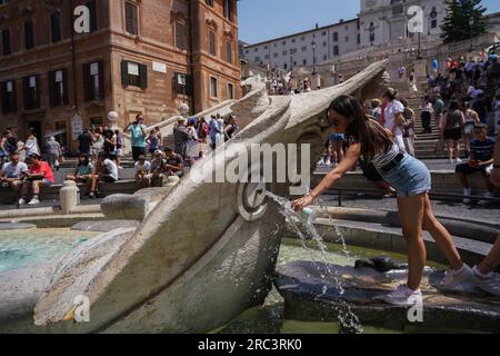 Rome, Italy. 12 July 2023   People cool off  at Fontana della Barcaccia, as Rome experiences high temperatures. The Italian health ministry has issued a red alert heatwave warning for eight major cities in Italy  as temperatures  are forecast to tip above 40°C/104F. Credit amer ghazzal/Alamy Live News Stock Photo