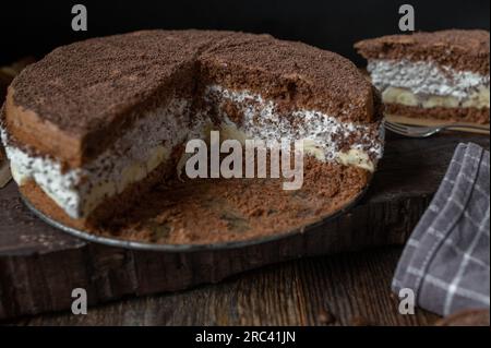 Chocolate cream cake with bananas on dark wooden background Stock Photo