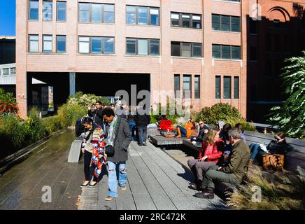 USA, New York, Manhattan, people seated and walking beside the water feature on the Sundeck leading to the Chelsea Market Passage on the High Line lin Stock Photo