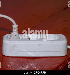 Old dirty extension cord on dirty parquet Stock Photo