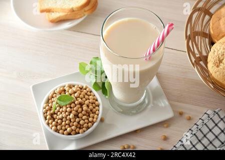 Soy drink in tall glass with soy beans in container on wooden bench in a kitchen. Elevated view. Stock Photo