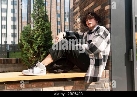 young man sits relaxed on a city bench Stock Photo