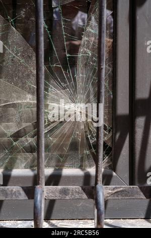 Shattered window glass with security bars close up Stock Photo