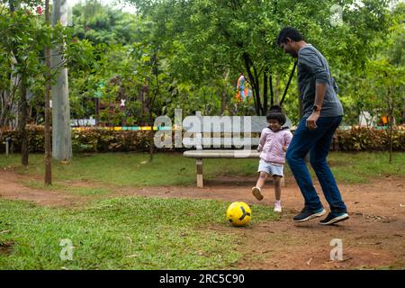 A heartwarming photo of a father and daughter playing football in the park. They are both smiling and laughing, and the photo captures the joy Stock Photo