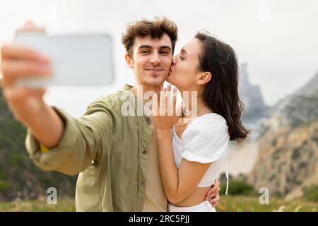 Happy loving couple after engagement taking selfie on cellphone, capturing perfect beachfront proposal Stock Photo