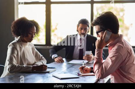 Concentrated multicultural colleagues gathering in boardroom, brainstorming Stock Photo