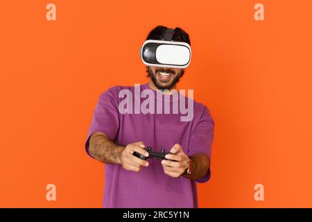 Middle eastern man playing video games, using VR glasses, joystick Stock Photo